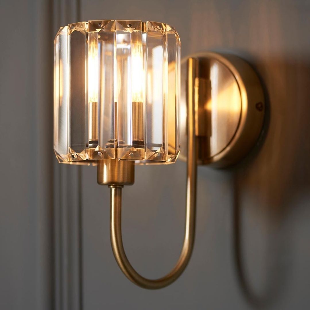 Luz de pared con brazo curvo, pantalla de vidrio facetado y acabado de latón antiguo