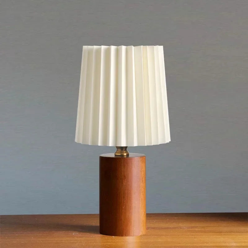 Lámpara de mesa con pantalla de tela plisada y base de madera maciza