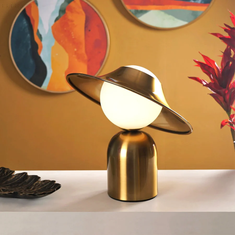 Lámpara de mesa de metal dorado con cabezal inclinado y luz cálida