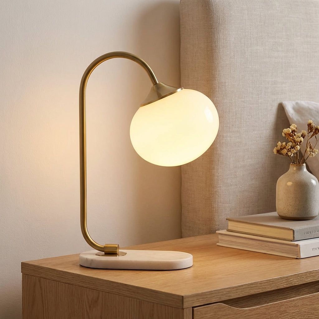 Lámpara de mesa con pantalla de vidrio redondeada y tallo metálico curvado
