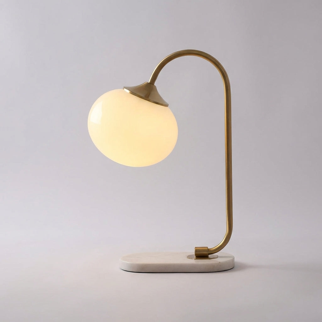 Lámpara de mesa con pantalla de vidrio redondeada y tallo metálico curvado