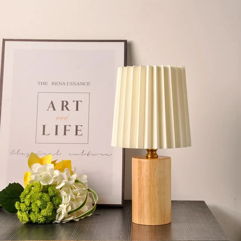 Lámpara de mesa con pantalla de tela plisada y base de madera maciza