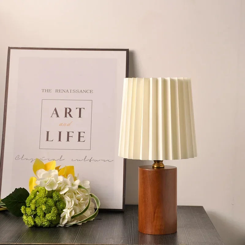 Lámpara de mesa con pantalla de tela plisada y base de madera maciza