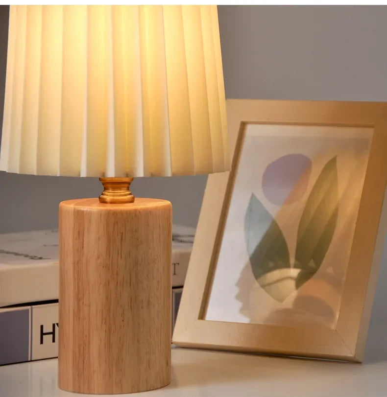 Lámpara de mesa con pantalla de tela plisada y base de madera maciza