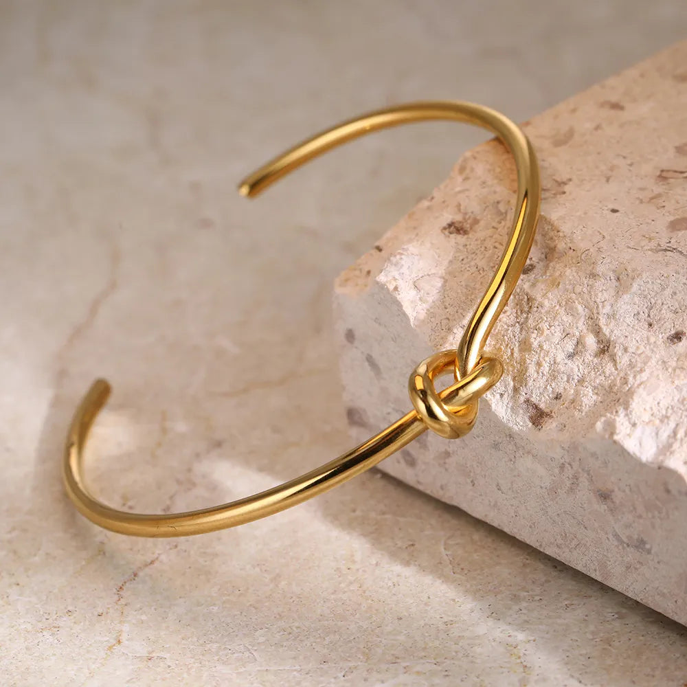 Brazalete de puño abierto chapado en oro con nudo retorcido