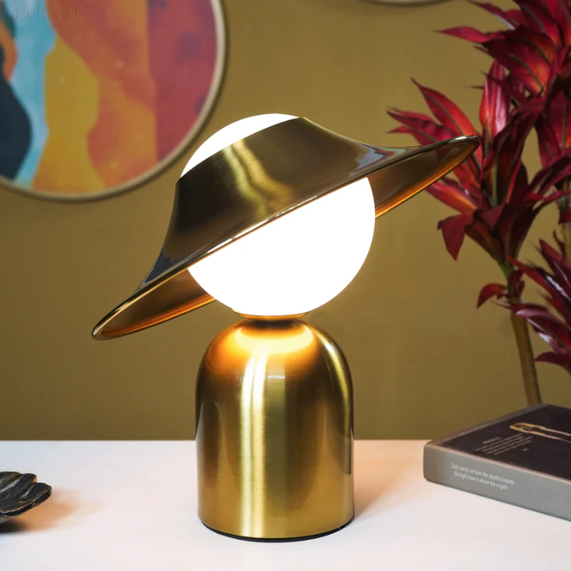 Lámpara de mesa de metal dorado con cabezal inclinado y luz cálida
