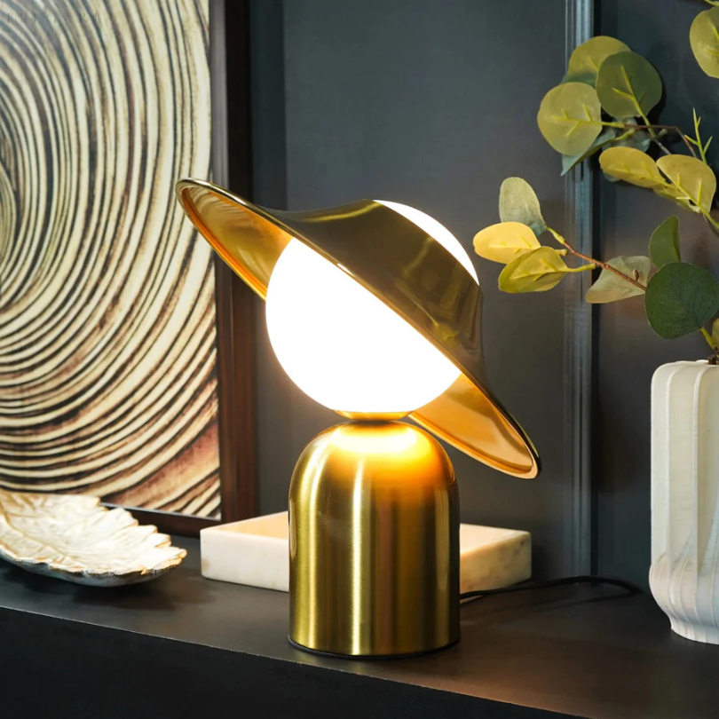 Lámpara de mesa de metal dorado con cabezal inclinado y luz cálida